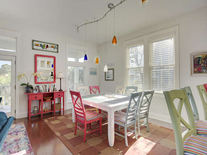 Bright Dining Space With Colorful Chairs, Suspended Lights, And Large Windows