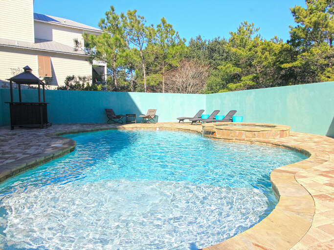 Vacation Rental Pool Flanked By Lounge Chairs And Leafy Trees