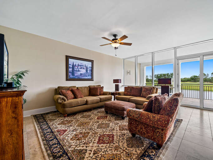Spacious Living Room With Sliding Doors To Balcony, Plush Sofas, And Ceiling Fan