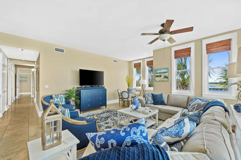 Bright Beachside Living Room With Blue And White Decor, Ceiling Fan, And Ocean Views