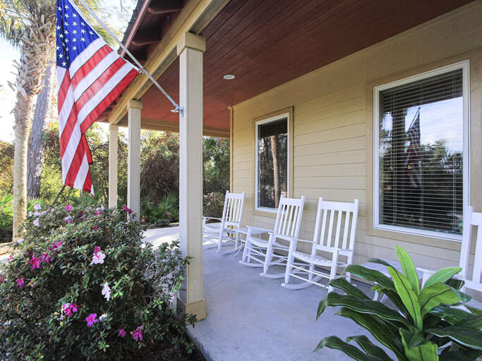Porch With Plants, American Flag, White Chairs, Wooden Beams