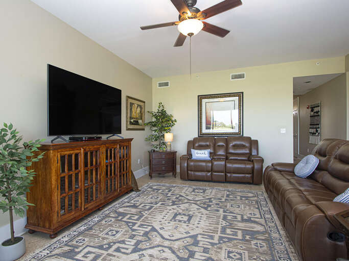 Living Space With Large Leather Sofa, Patterned Rug, And Wooden Cabinetry