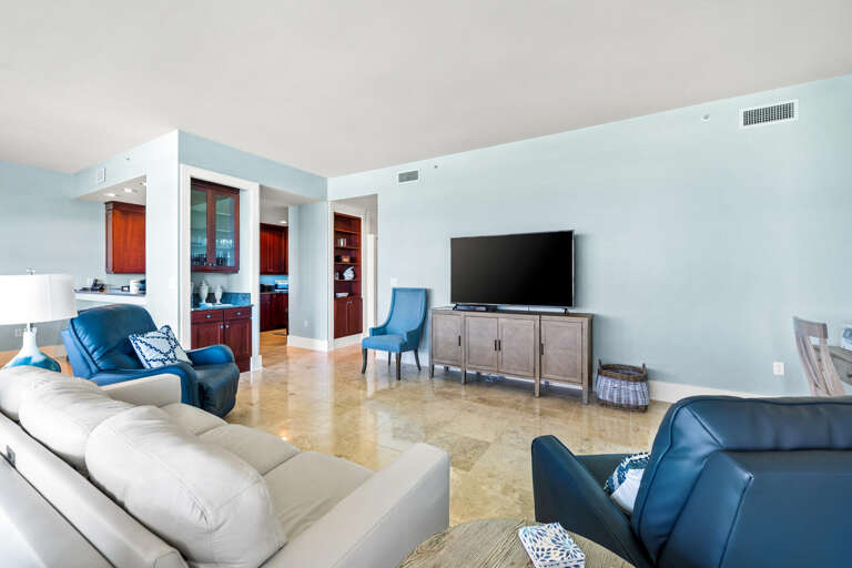 Spacious Living Room With Blue Chairs, Beige Couch, And Large TV