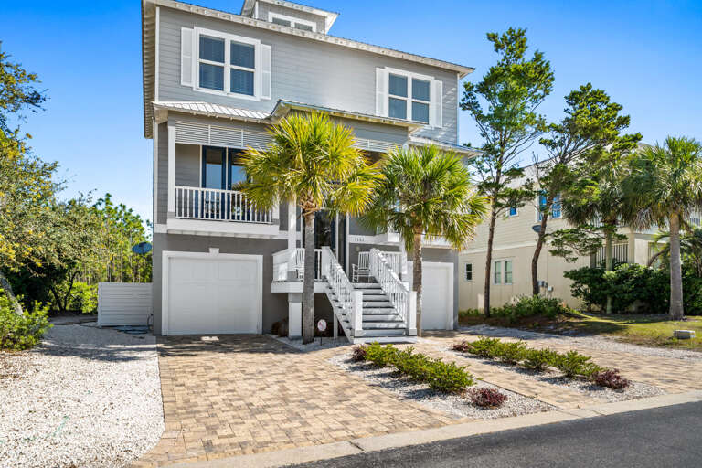 Three-story Vacation Rental With Palm Trees And Paved Driveway