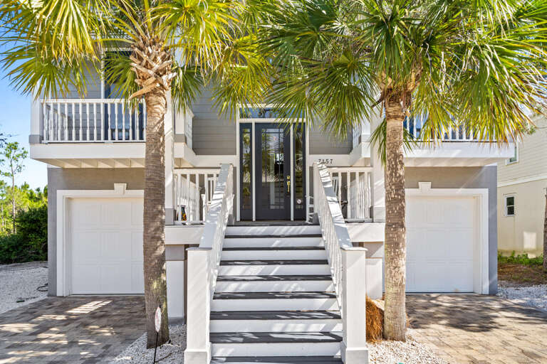 Palm-fringed Pathway Leading To A Pristine White Building With Balconies