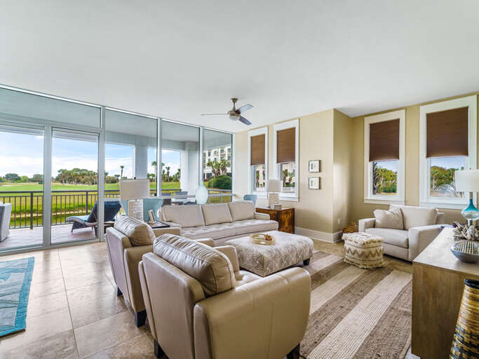 Spacious Living Area With Plush Sofas, Glass Doors To A Green Golf Course View