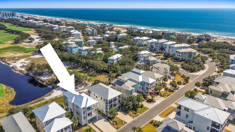 Aerial View Of Coastal Community With Homes Near Beach And Pond