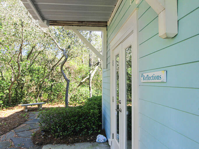Turquoise Building Entrance Under White Wooden Eaves Surrounded By Shady Greenery