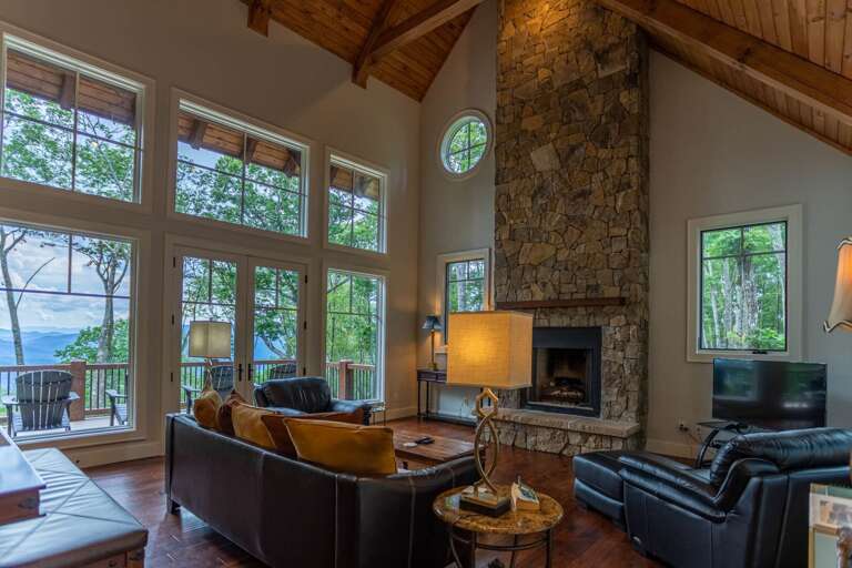 Living Room With Fireplace, Sofas, And Large Windows Showing Trees Outside Living Room With Fireplace, Sofas, And Large Windows Showing Trees Outside