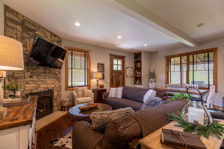 Living Room With Stone Fireplace And Mounted Television