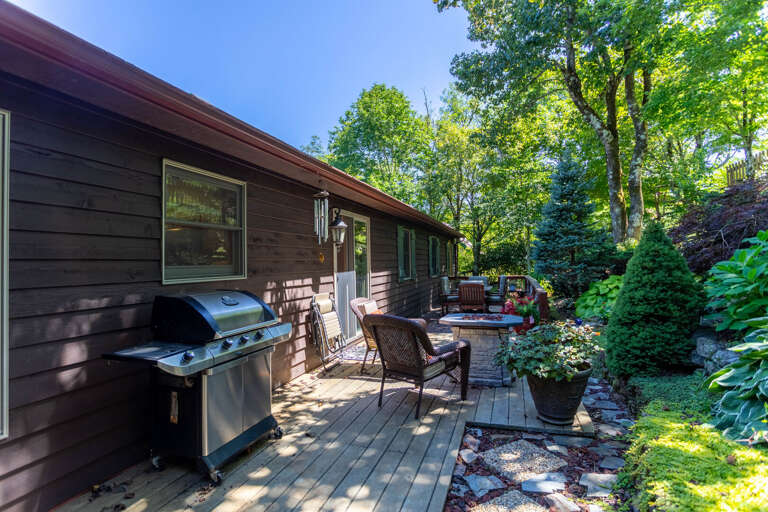 Main level back deck with firetable, dining table, gas grill, Big Green Egg, and manmade waterfall feature Main level back deck with firetable, dining table, gas grill, Big Green Egg, and manmade waterfall feature