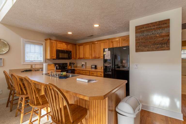 Residential Kitchen With Wooden Cabinetry And Bar Stools