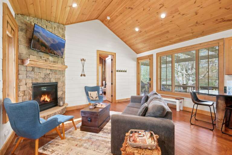 Gather around the stone fireplace under soaring wood-planked ceilings, with the wooded deck just steps away.
