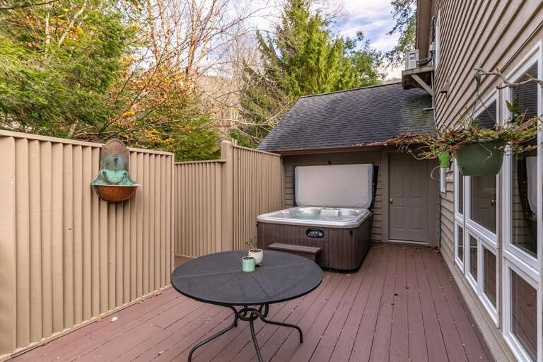 Wooden Deck With Hot Tub And Round Table, Bordered By Beige Fence