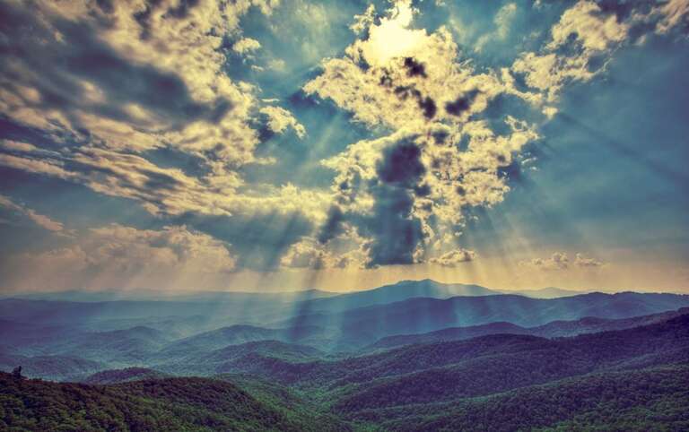 Sunrays Breaking Through Clouds Over Mountain Range