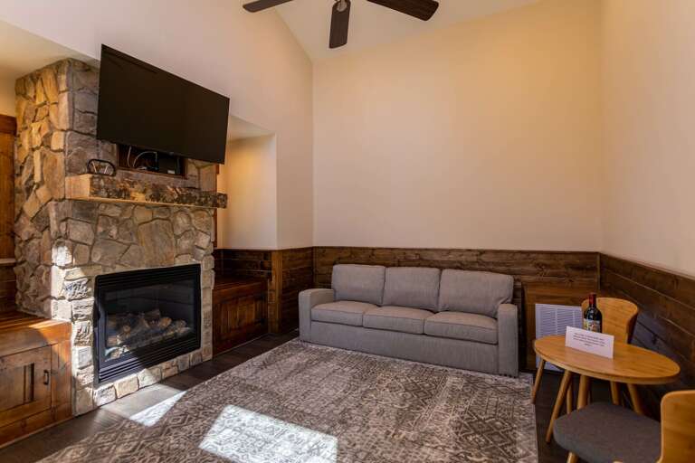 Living Room With Sofa, Stone Fireplace, And Television