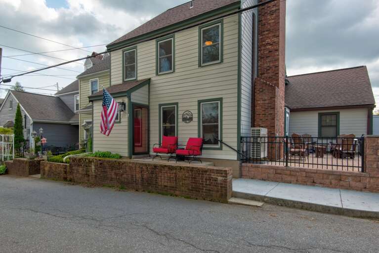 Two-story Residential Building With American Flag And Red Chairs