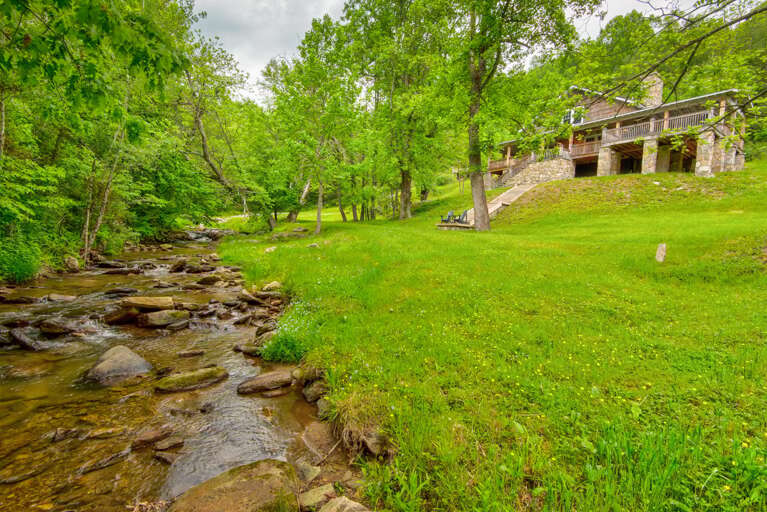 Stone House By A Stream Surrounded By Greenery