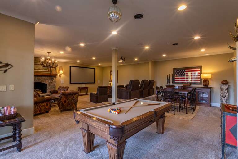 Lower level theater room and seating area with game table and pool table.