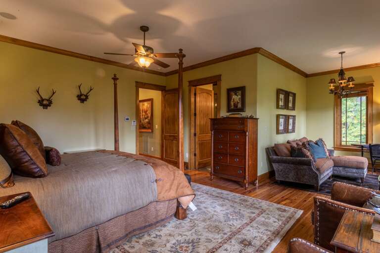 Main level master bedroom with king sized bed, smart TV, seating area and full bathroom.