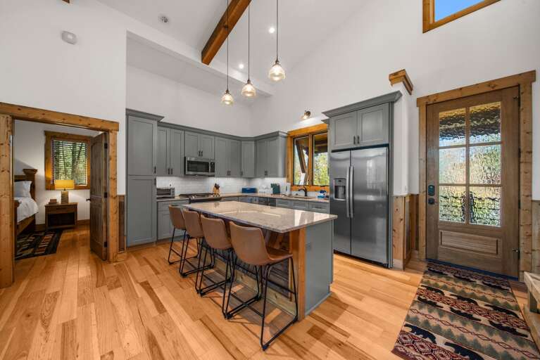 Spacious Kitchen With Wooden Floors, Island Seating, And Pendant Lighting