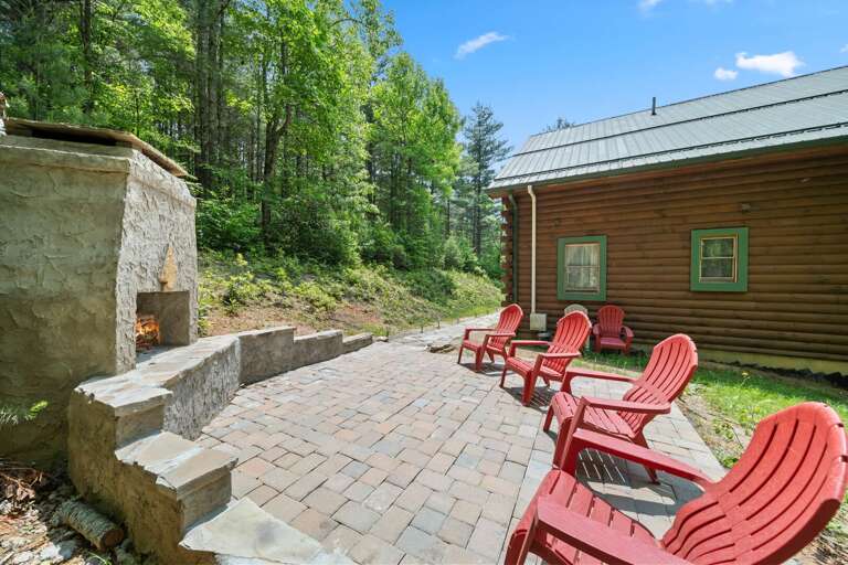 Red Chairs Resting On Rustic Patio, Pines Peeking Behind