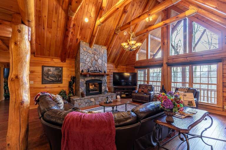 Wood-paneled Living Room With Stone Fireplace And Large Windows