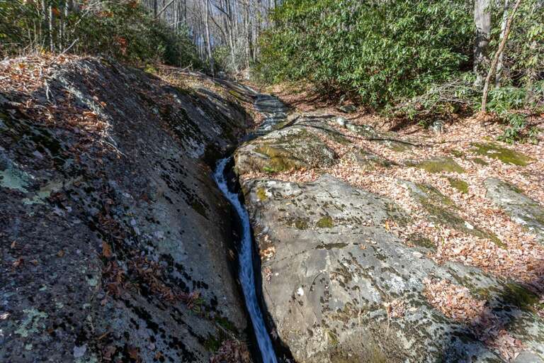 A highlight of this home is the easy walk along the gravel road to the small waterfall that cascades over large boulders and under the wooden bridge.