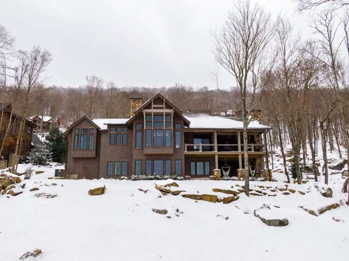 Snowy Scene Showing A Spacious Vacation Rental Surrounded By Bare Trees