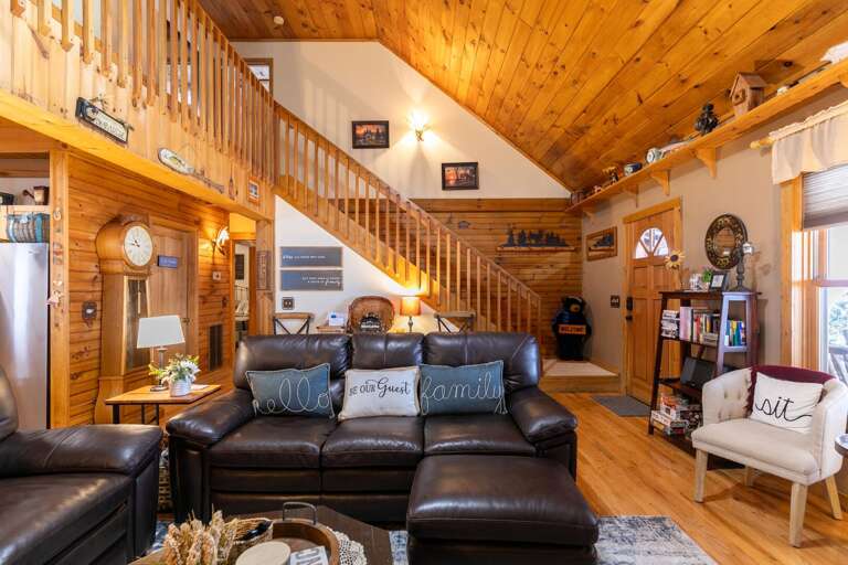 Wood-paneled Living Space With Leather Sofas, Staircase, And Clocks