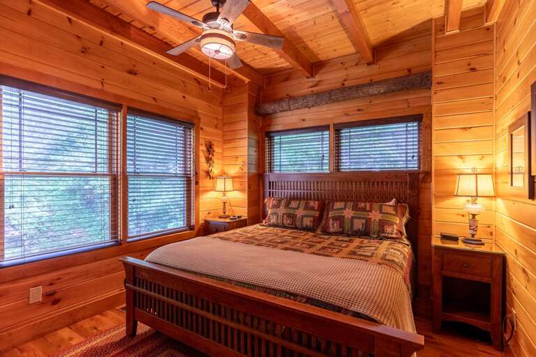 King bedroom on the main level with wood beams and a cozy atmosphere.