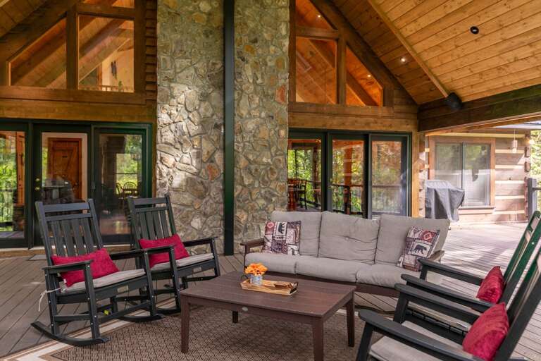 Spacious Porch With Plush Sofas And Rocking Chairs, Pillared By Sturdy Stone Columns, Under A Timber Ceiling