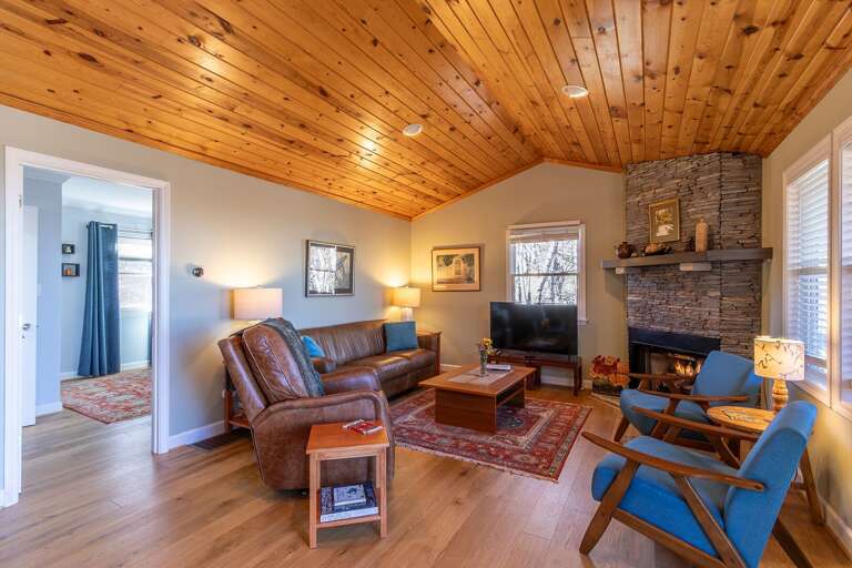 Vacation Rental Room With Wooden Ceiling And Stone Fireplace, Furnished With Leather And Blue Chairs