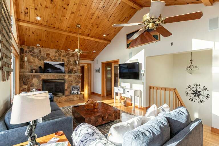 Wood-clad Ceiling, Stone Hearth, Plush Sofas In Well-lit Living Space