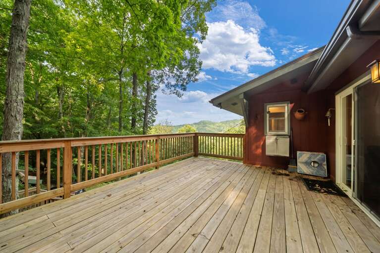 Settle in after a summer rain and take in those layered Blue Ridge ridgelines right from the deck.   Wood deck with seating and layered mountain views at A Red Chalet in Linville NC
