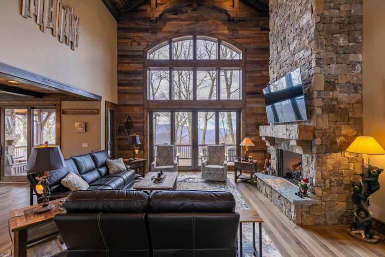 Vacation Rental Living Room With Large Windows, Leather Sofas, And Stone Fireplace