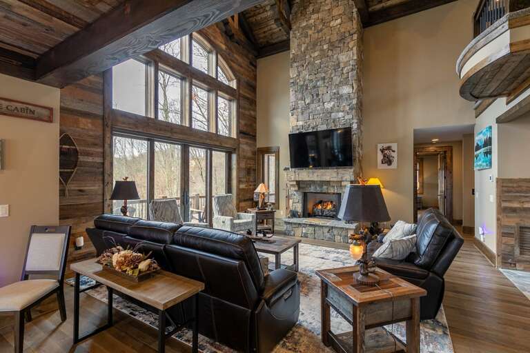 Spacious Living Room With Stone Fireplace, Black Sofas, And Wooden Beams