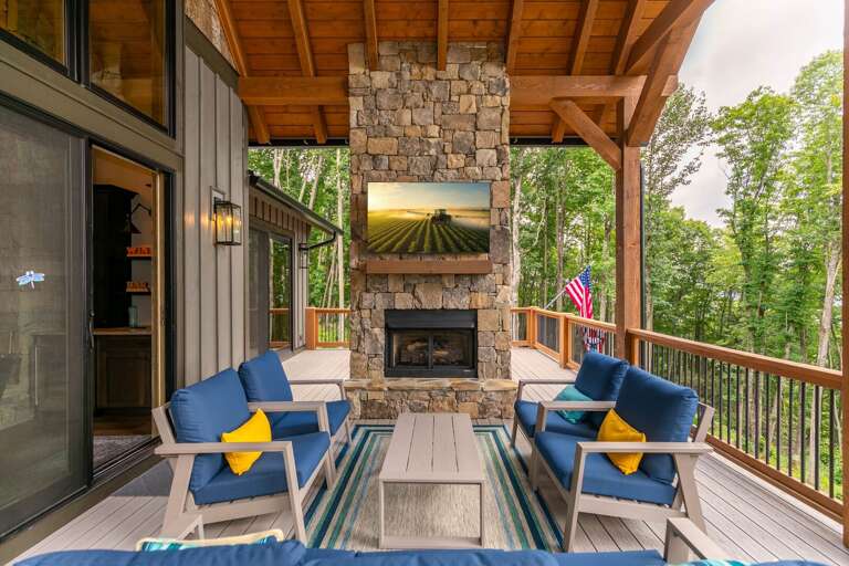 Vacation Rental Veranda With Vibrant Chairs, Visible Verdant Vista, And A Stone Fireplace