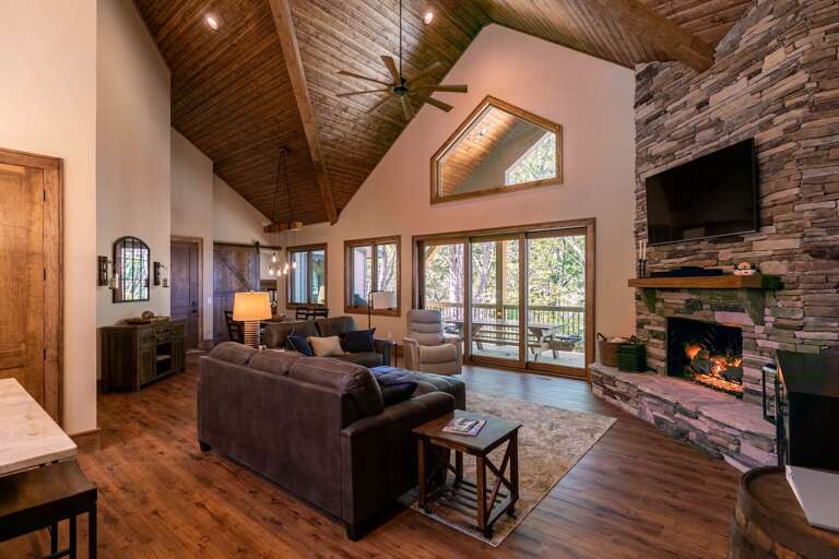 Spacious Living Space With Stone Fireplace And Forest View Through Large Windows