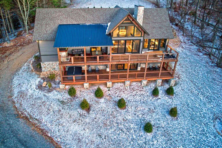 Snow-dusted Structure Surrounded By Slender Trees, Showcasing A Series Of Sizable Windows And A Slate-colored Roof