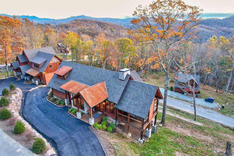 Aerial View Of Rustic Cabins Nestled Among Autumn Trees, With Winding Road