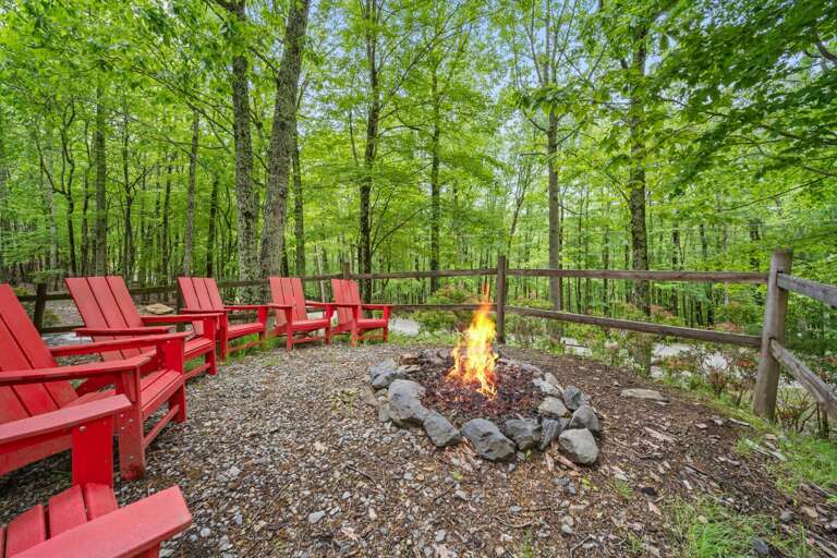 Red Chairs Around A Fire Pit In A Lush Forest Setting