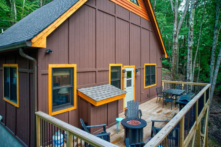 Wood-clad House Hidden In Thick Trees With Deck And Furniture