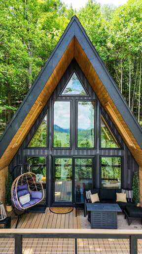 Tucked into the trees of Boone, this striking A-frame welcomes you with a soaring glass facade and a shaded lower patio with a hot tub.