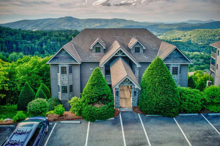 A welcoming craftsman-style entry framed by towering evergreens at Sweet Sugar Views At The Reserve II on Sugar Mountain.