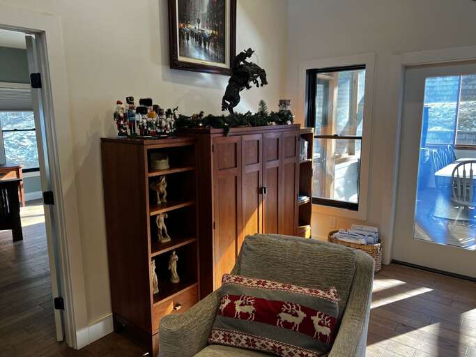 Sunlit Space With Shelves, Sculptures, And A Seated Spot, Showcasing Sliding Doors And Lake View