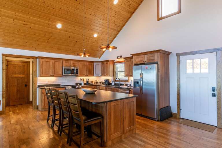 Spacious Kitchen Interior, Wooden Ceiling, Sleek Bar Stools, Stainless Steel Appliances