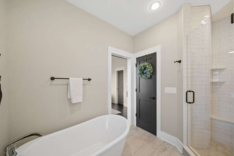 Vacation Rental Bathroom With White Tub, Tiled Shower, Hanging Towels