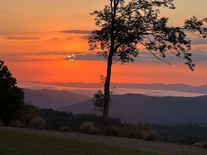 Sunset View From Vacation Rental Showcasing Skys Crimson Canvas And Serene Mountain Silhouette