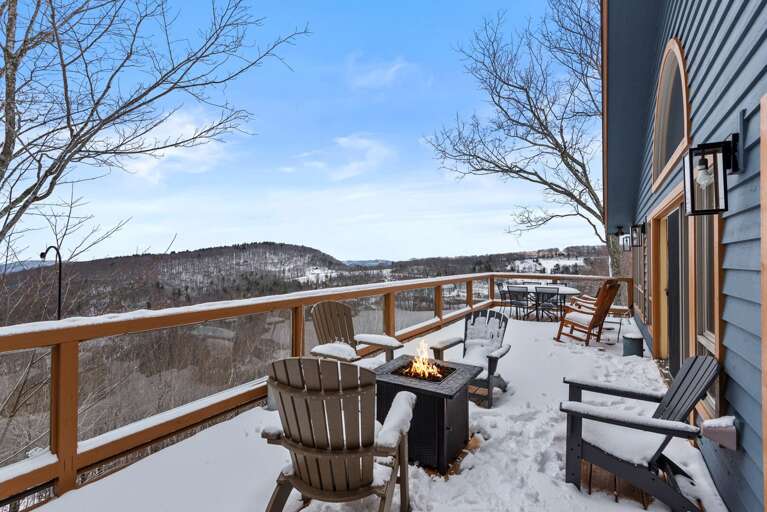 Snowy Scene With Seating And Fire Pit On Vacation Rental Balcony Overlooking Hills